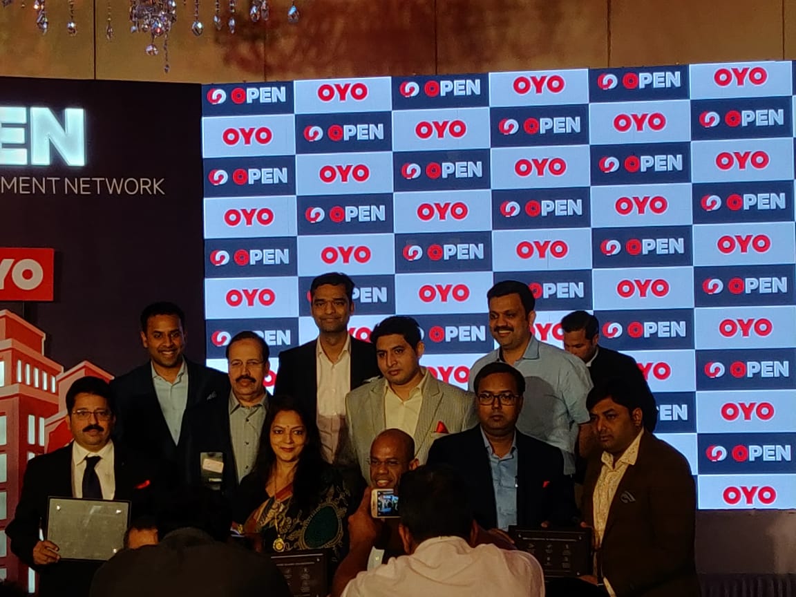 Ex.08 — OYO OPEN launch, group photo against the step-and-repeat